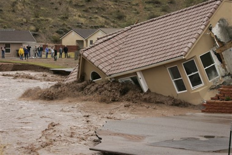 A house in the Beaver Dam Resort area falls into the Beaver Dam Wash in Beaver Dam, Ariz. Tuesday, Dec. 21, 2010. Heavy rains caused the wash to swell over its banks destroying roads and homes along it's path. (AP Photo/Las Vegas Review-Journal, John Locher)